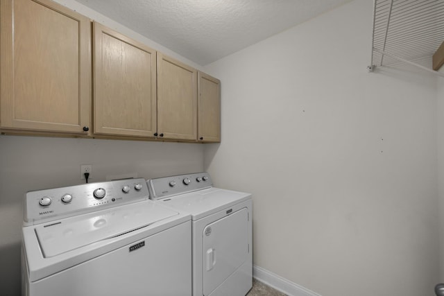 washroom with washing machine and clothes dryer, cabinet space, a textured ceiling, and baseboards