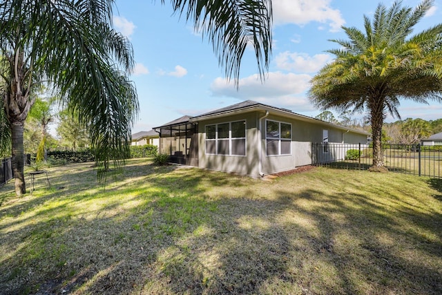 back of property with stucco siding, a yard, and fence