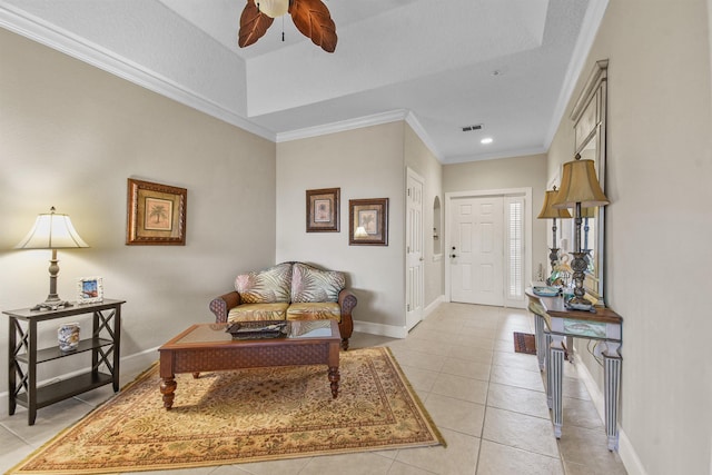 interior space with a tray ceiling, ceiling fan, ornamental molding, and light tile patterned flooring