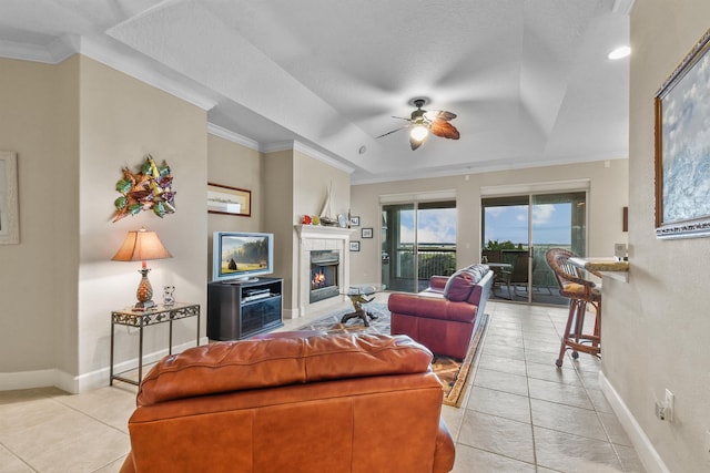 tiled living room with a textured ceiling, ceiling fan, a raised ceiling, and crown molding