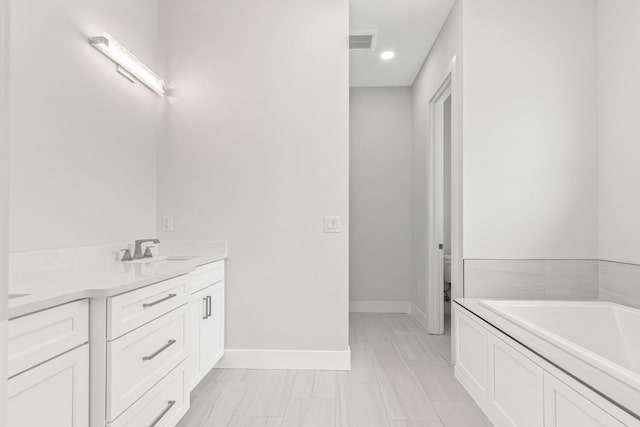 bathroom featuring vanity, a bathtub, and toilet