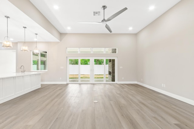 unfurnished living room with french doors, sink, ceiling fan, and light hardwood / wood-style floors