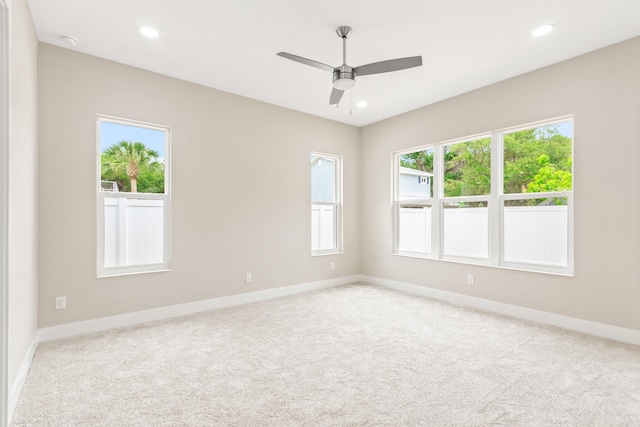 spare room with a wealth of natural light, light colored carpet, and ceiling fan