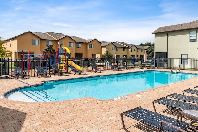 view of swimming pool featuring a playground and a patio