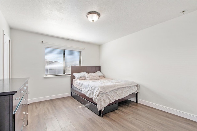 bedroom with a textured ceiling and light hardwood / wood-style flooring