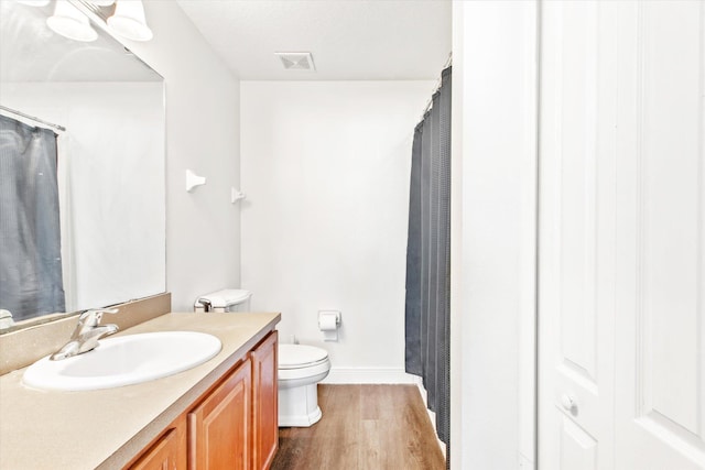 bathroom featuring toilet, vanity, and hardwood / wood-style flooring