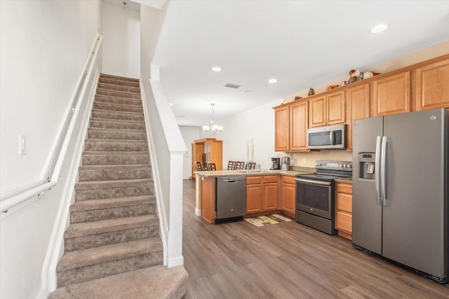 kitchen featuring stainless steel appliances, sink, hardwood / wood-style flooring, a notable chandelier, and hanging light fixtures