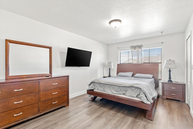 bedroom with light wood-type flooring and a textured ceiling