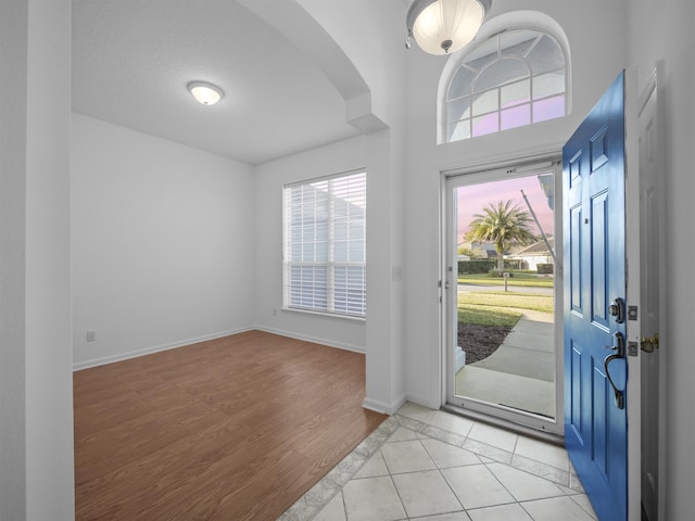 tiled foyer entrance featuring arched walkways and baseboards