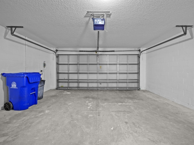 garage featuring concrete block wall and a garage door opener