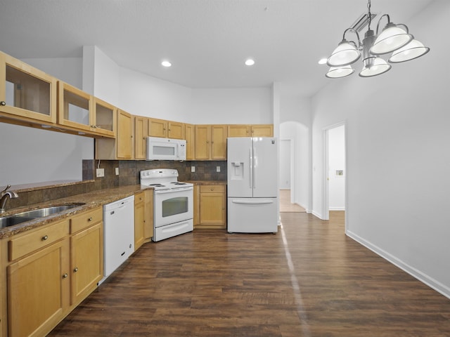 kitchen featuring arched walkways, decorative light fixtures, white appliances, a sink, and glass insert cabinets