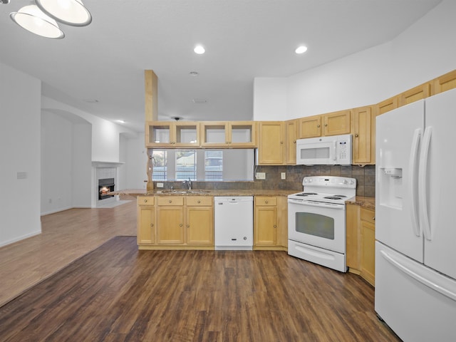 kitchen featuring glass insert cabinets, open floor plan, a sink, a warm lit fireplace, and white appliances