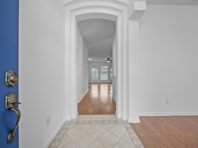 hall featuring light wood-style flooring and baseboards