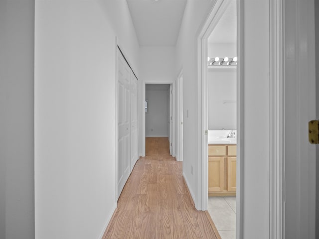 corridor featuring light wood-style flooring and baseboards