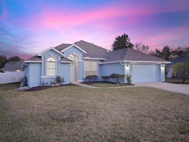 ranch-style home with concrete driveway, stucco siding, an attached garage, and a front yard