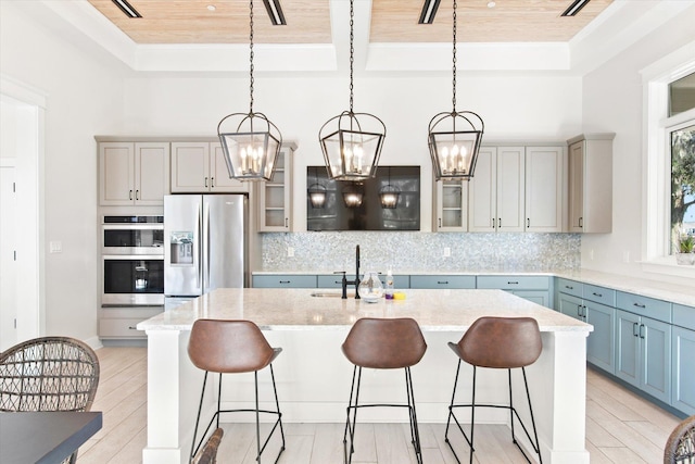 kitchen with pendant lighting, wood ceiling, an island with sink, and appliances with stainless steel finishes