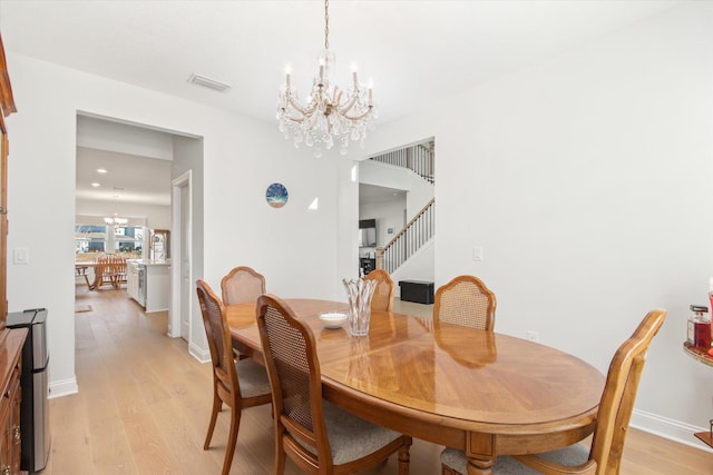 dining area with a notable chandelier and light hardwood / wood-style floors