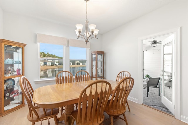 dining area featuring an inviting chandelier, a water view, and light wood-type flooring