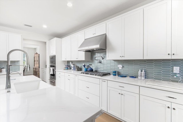 kitchen with backsplash, appliances with stainless steel finishes, sink, and white cabinets