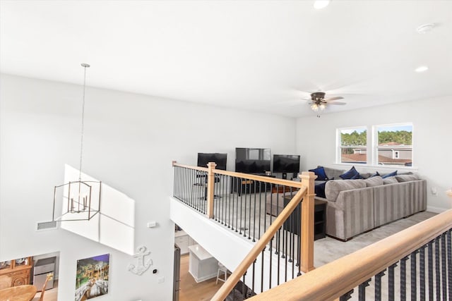 living room with ceiling fan with notable chandelier and light hardwood / wood-style flooring