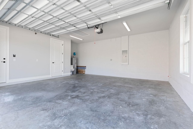 garage with concrete block wall, a garage door opener, and electric panel