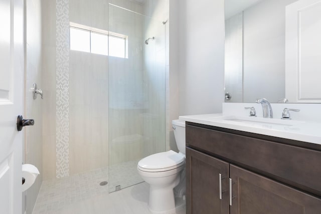 full bath with toilet, vanity, and a tile shower