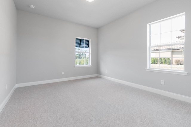 carpeted empty room featuring baseboards and a healthy amount of sunlight