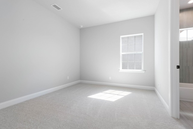 carpeted spare room with visible vents and baseboards
