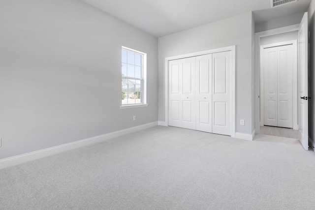 unfurnished bedroom with visible vents, baseboards, a closet, and light colored carpet
