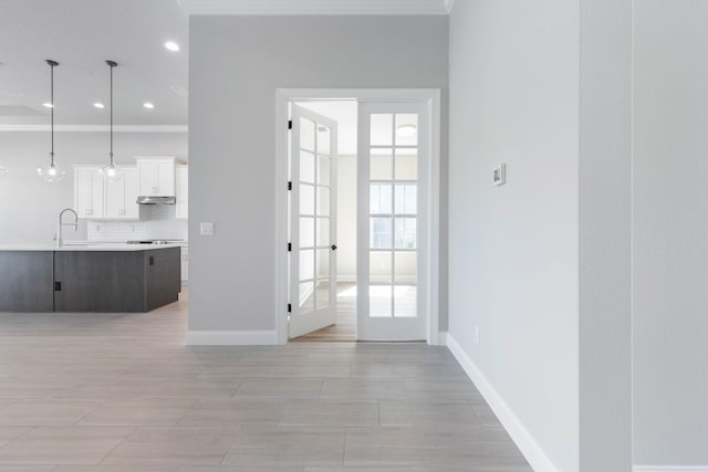doorway to outside featuring crown molding, baseboards, recessed lighting, and a sink