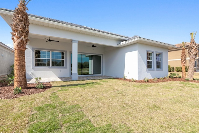 rear view of house featuring stucco siding, a lawn, and ceiling fan