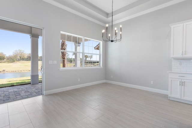 unfurnished dining area with a water view, ornamental molding, baseboards, and an inviting chandelier
