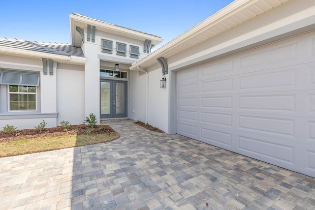 entrance to property featuring french doors, driveway, and stucco siding