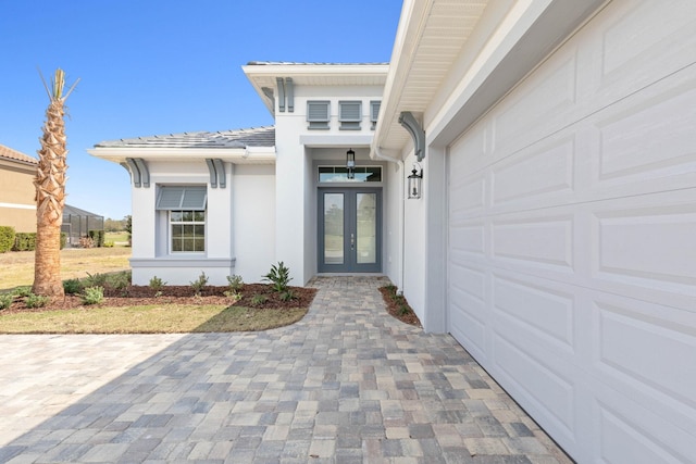 doorway to property featuring french doors, a garage, and stucco siding