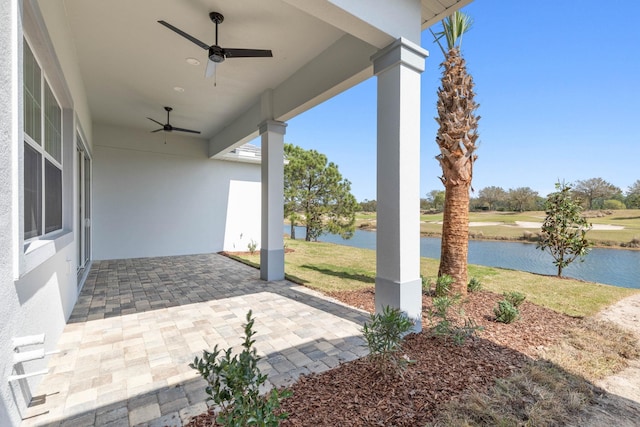 view of patio with a water view and a ceiling fan