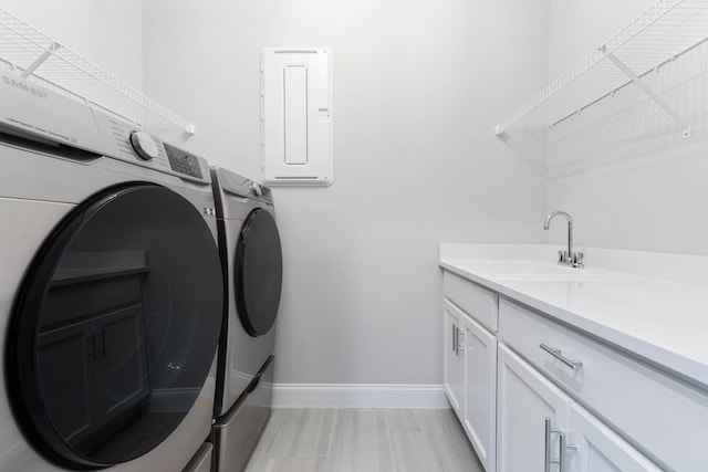 laundry room with a sink, baseboards, cabinet space, and separate washer and dryer