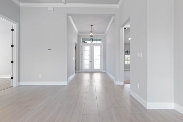 entryway with french doors, ornamental molding, baseboards, and light wood-style flooring