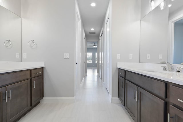 bathroom with baseboards, two vanities, a sink, and visible vents