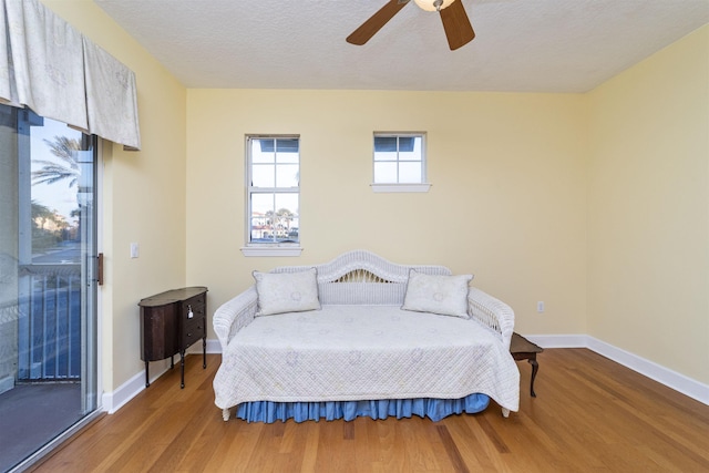 bedroom featuring hardwood / wood-style flooring, ceiling fan, access to exterior, and a textured ceiling