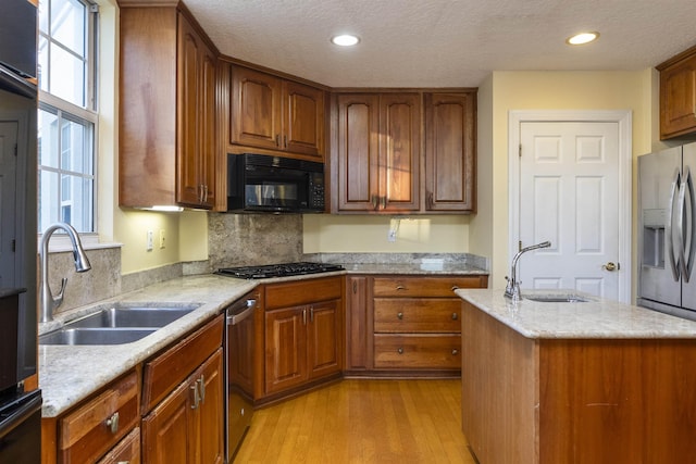 kitchen featuring a textured ceiling, light wood-type flooring, stainless steel appliances, and sink