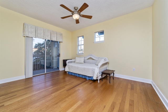 bedroom featuring access to outside, ceiling fan, hardwood / wood-style floors, and a textured ceiling