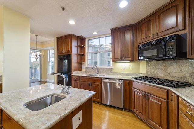 kitchen with black appliances, sink, a kitchen island with sink, and a chandelier