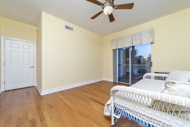 bedroom with a textured ceiling, access to outside, light hardwood / wood-style flooring, and ceiling fan