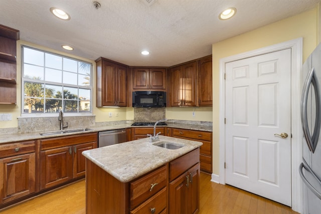 kitchen with appliances with stainless steel finishes, light hardwood / wood-style flooring, a kitchen island with sink, and sink