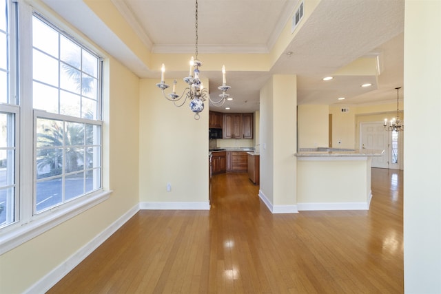 kitchen with decorative light fixtures, a raised ceiling, light hardwood / wood-style flooring, and a chandelier