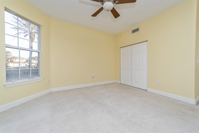 unfurnished bedroom with light carpet, a closet, and ceiling fan