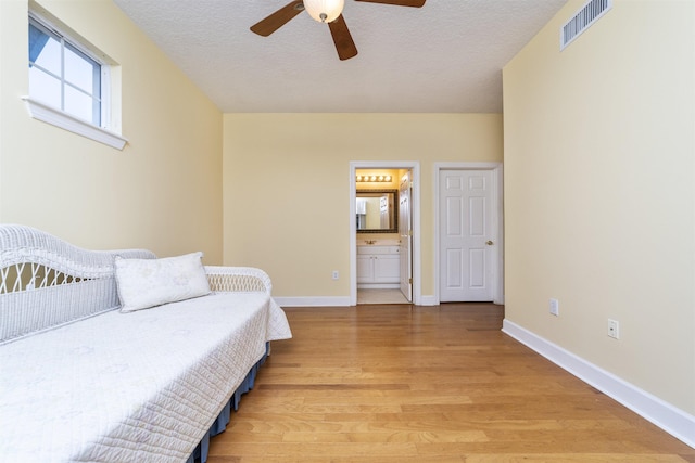 bedroom featuring a textured ceiling, light hardwood / wood-style floors, ceiling fan, and ensuite bathroom