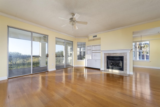 unfurnished living room featuring a tile fireplace, plenty of natural light, a textured ceiling, and hardwood / wood-style flooring