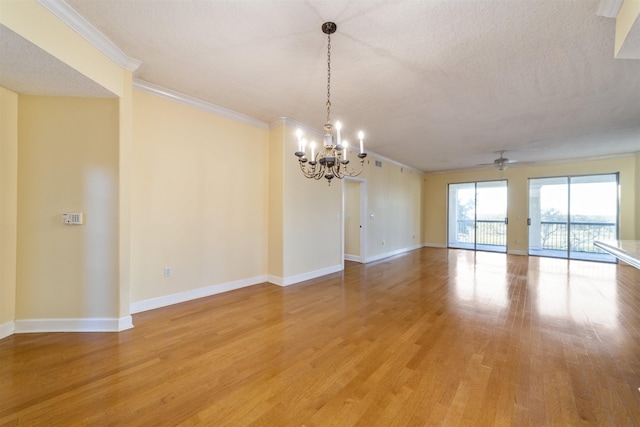 empty room featuring wood-type flooring, ceiling fan with notable chandelier, a textured ceiling, and ornamental molding