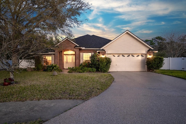 single story home with aphalt driveway, an attached garage, fence, a front lawn, and brick siding